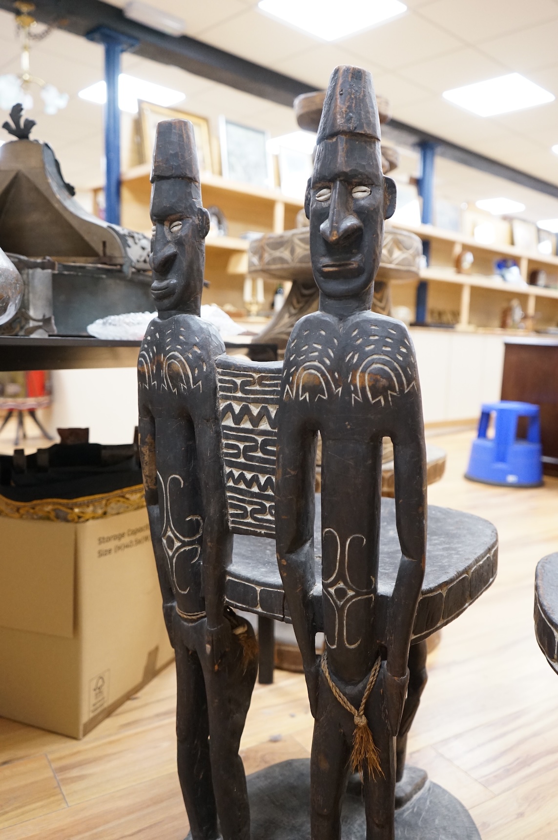 Papua New Guinea Sepik River, a near pair of ‘ceremonial’ figural chairs, each carved from a single section of a tree trunk with integral male and female backs and an castor figure front support with cowrie shell eyes. H